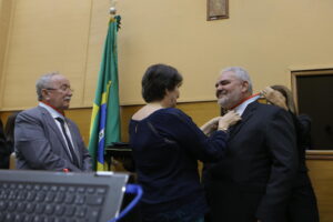 Maria Mendonça coloca a medalha no professor Milton Coelho